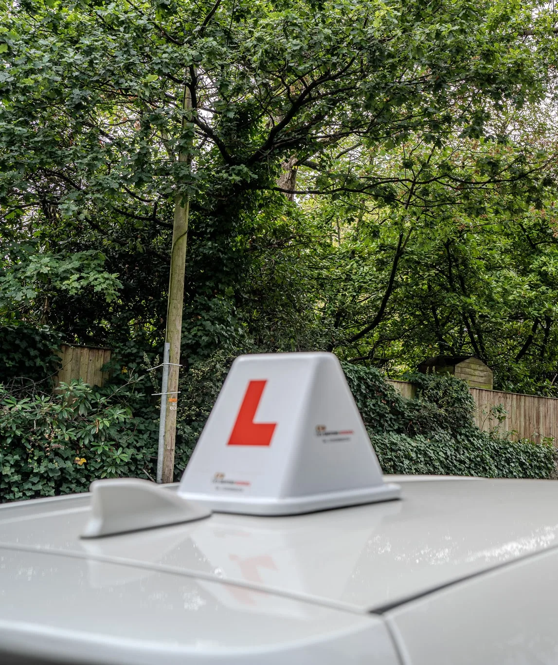 A learner car's L-plate roof sign on a leafy street in Edgbaston, Birmingham